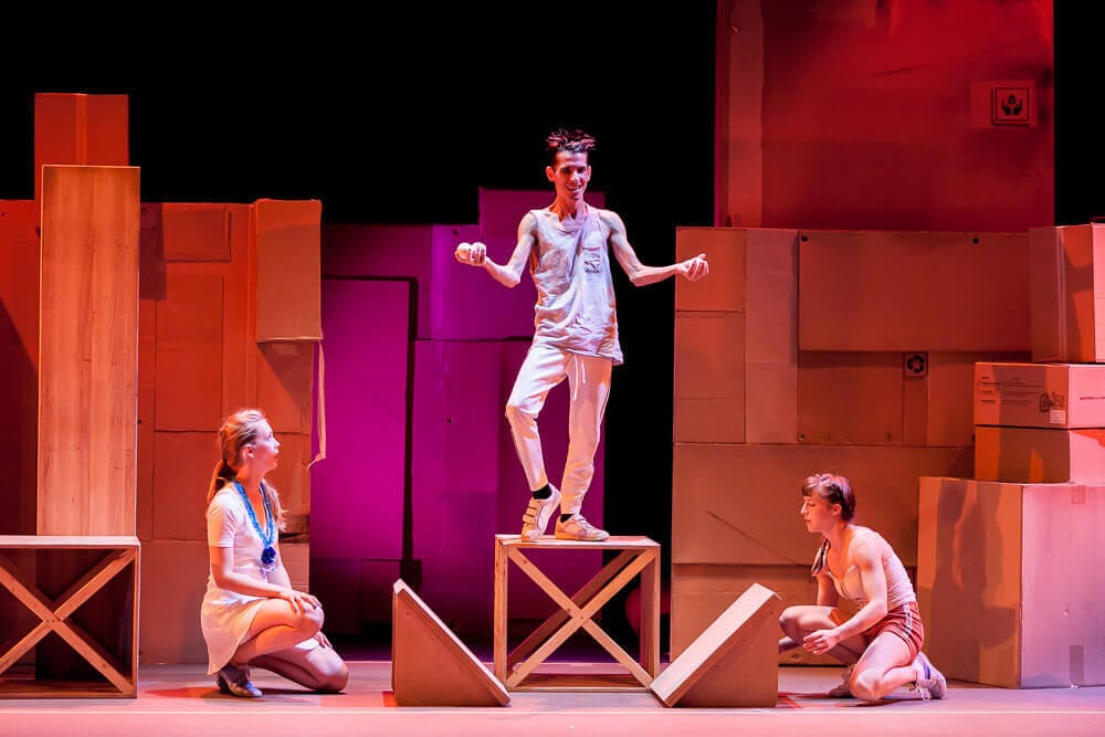 Artista realizando malabares de rebote sobre una plataforma de madera en el espectáculo Ludo.