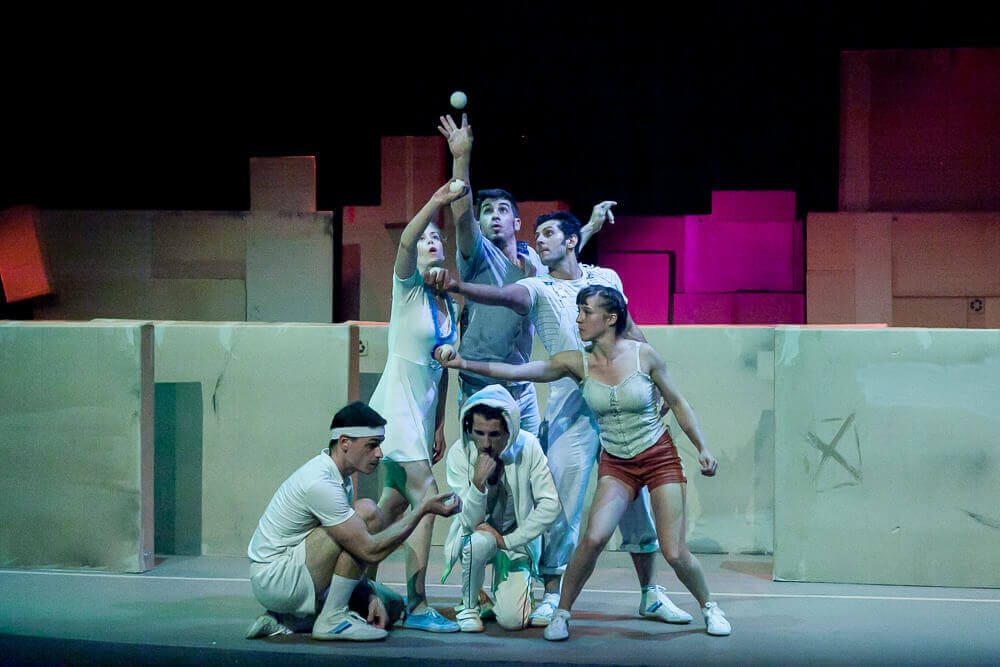 Elenco de Ludo Circus Show en una formación coral con malabares y acrobacias en el escenario.